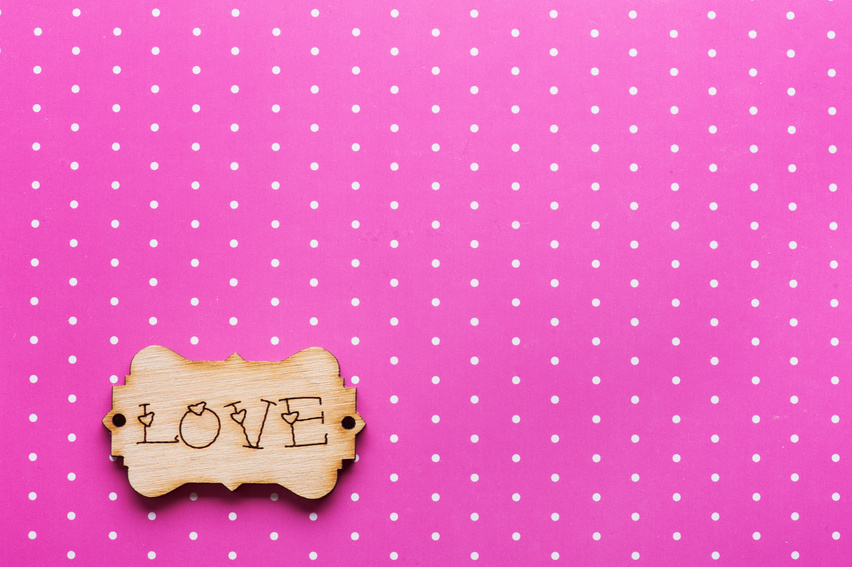 Wooden Tag With Word Love On Pink Polka Dot Background